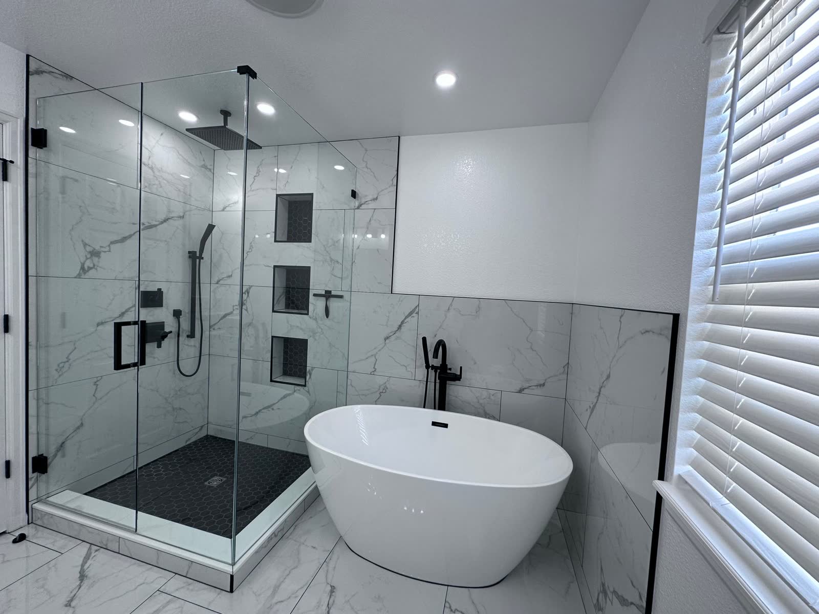 Marble-look bathroom with freestanding tub and glass shower