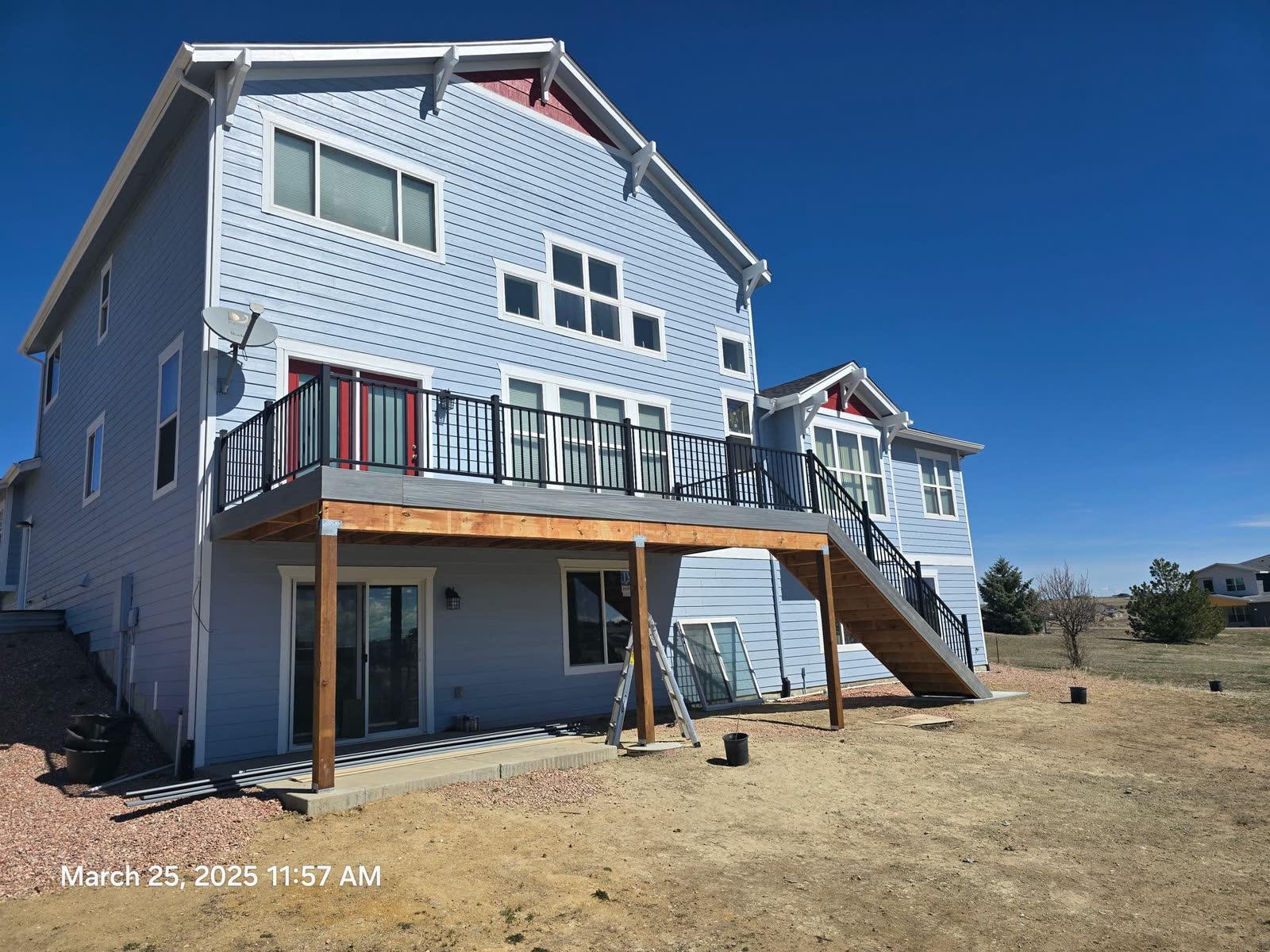 Elevated deck with black railing and stairs on a blue house