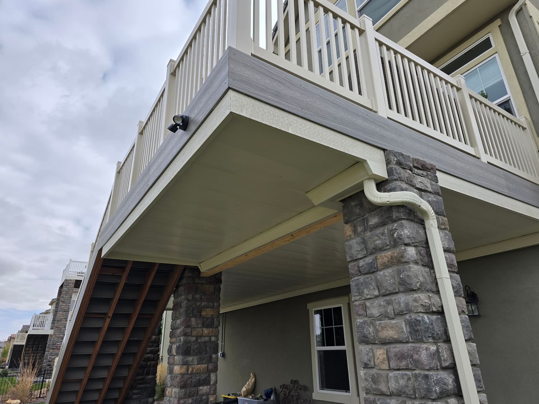 Second-storey deck on stone-clad pillars with a finished ceiling below