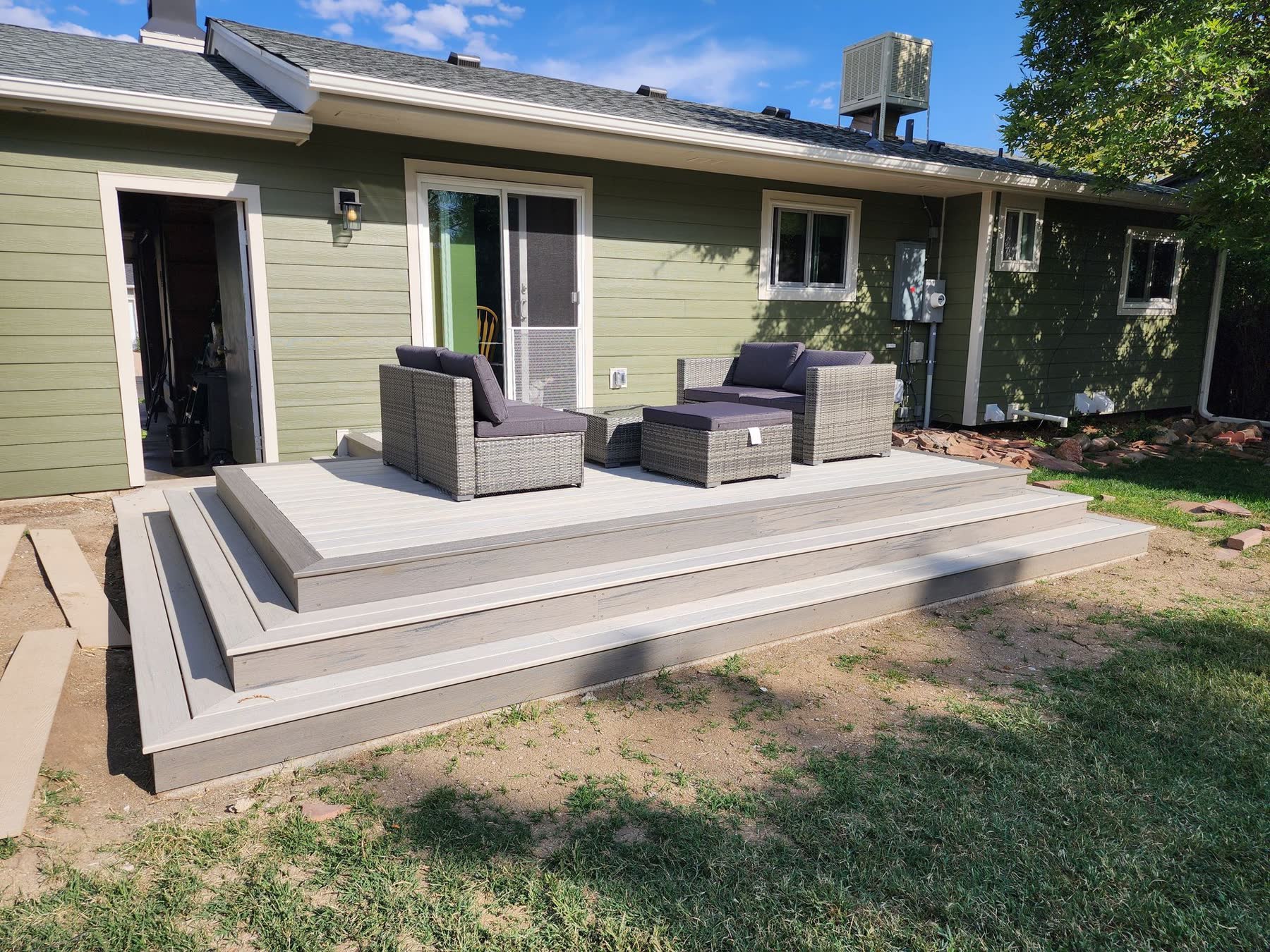 Composite deck with wraparound steps behind a green house