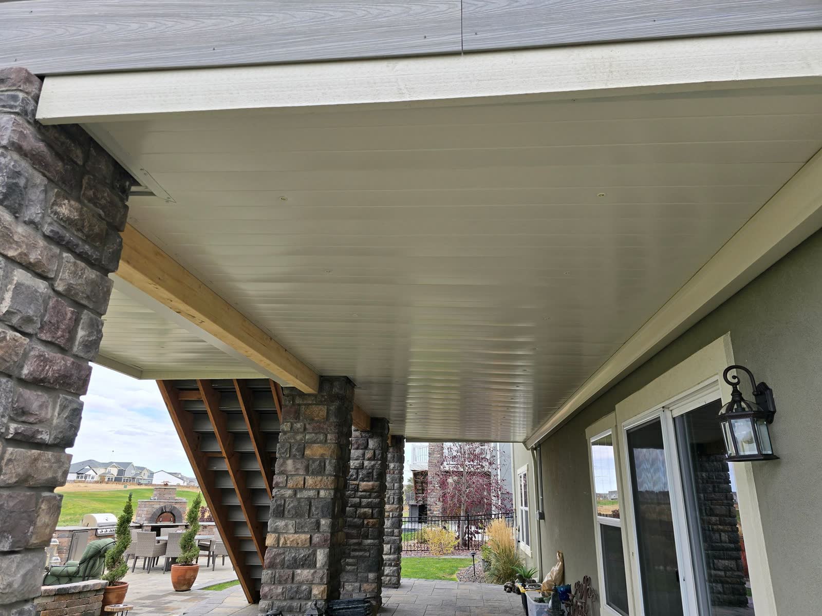 Covered patio under a deck with stone columns