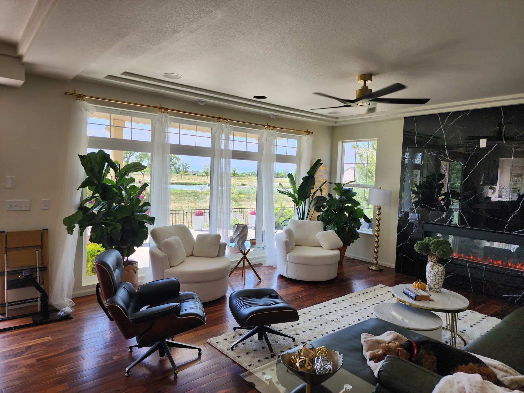 Same living room after the remodel, with a full wall of new windows and a black marble fireplace